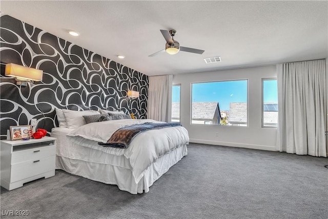 bedroom featuring carpet floors, visible vents, an accent wall, baseboards, and wallpapered walls