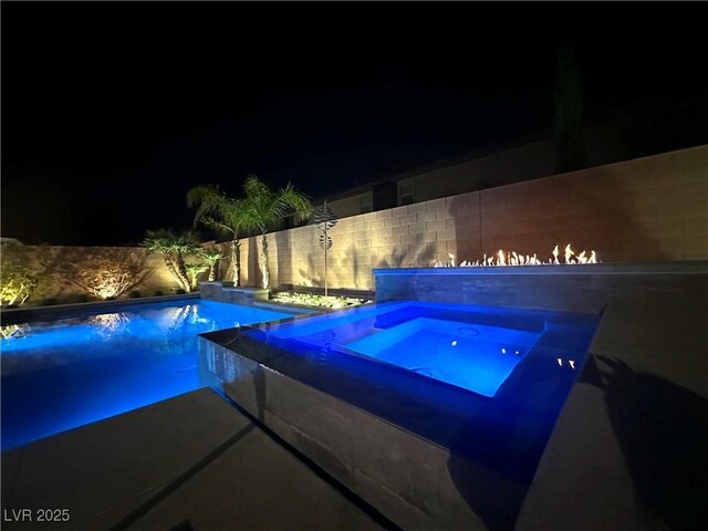 pool at twilight with an infinity pool, fence, and an in ground hot tub