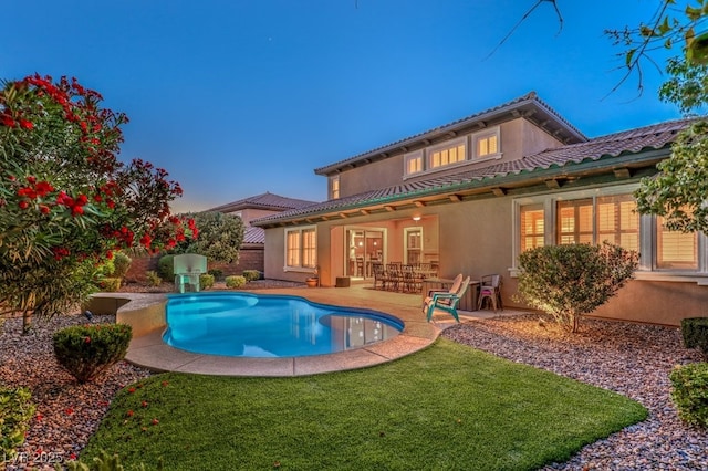 pool at dusk featuring a lawn and a patio