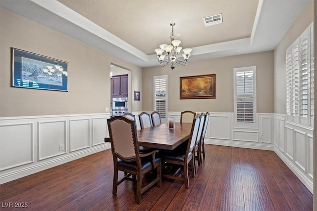 dining room with a raised ceiling, dark hardwood / wood-style floors, and a chandelier