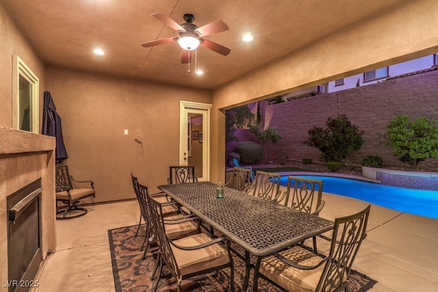 dining area with a tile fireplace and ceiling fan