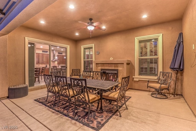 carpeted dining space featuring ceiling fan and a fireplace