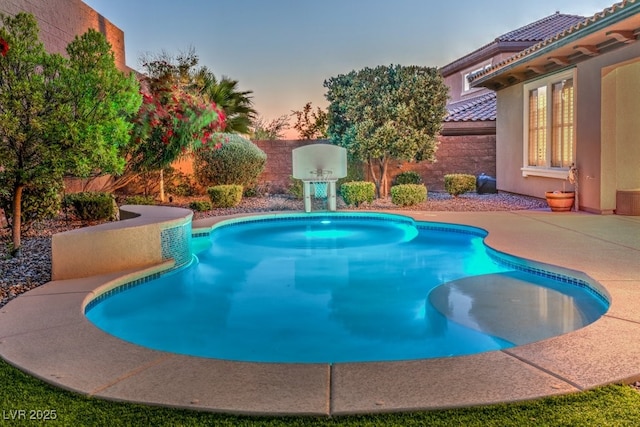 pool at dusk featuring a patio area