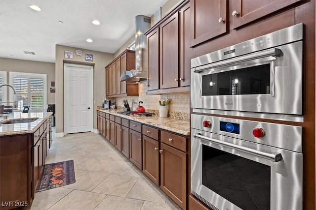 kitchen featuring stainless steel appliances, light stone countertops, sink, and backsplash