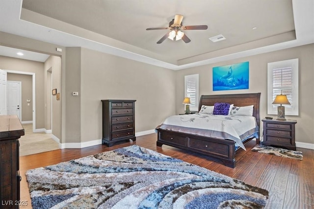 bedroom featuring dark wood-type flooring, ceiling fan, and a tray ceiling