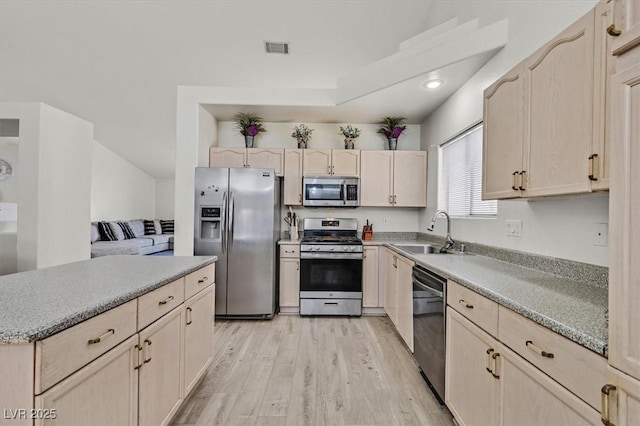 kitchen featuring appliances with stainless steel finishes, light brown cabinetry, sink, and light hardwood / wood-style flooring