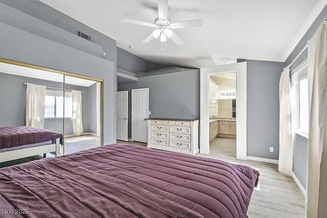 bedroom with vaulted ceiling, light hardwood / wood-style flooring, ceiling fan, ensuite bath, and a closet