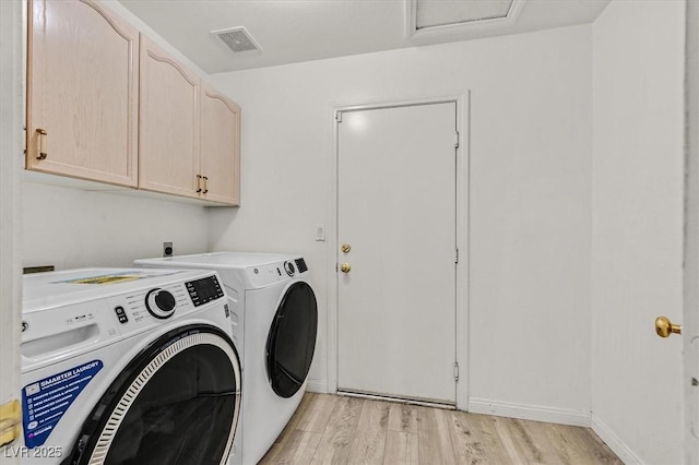 clothes washing area with independent washer and dryer, cabinets, and light wood-type flooring