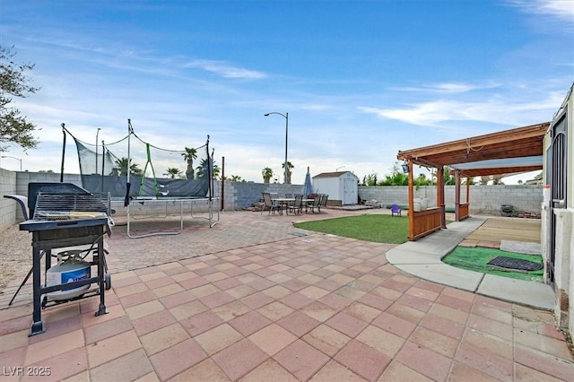 view of patio with a trampoline and a storage unit