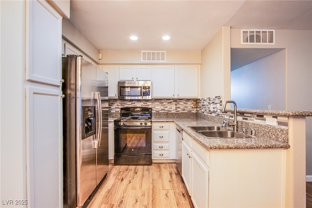 kitchen with sink, tasteful backsplash, light wood-type flooring, stainless steel appliances, and white cabinets