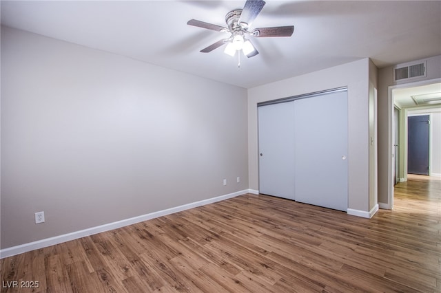 unfurnished bedroom featuring hardwood / wood-style floors, a closet, and ceiling fan