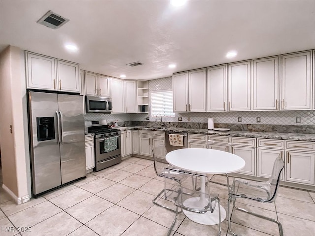 kitchen featuring tasteful backsplash, sink, light tile patterned floors, and appliances with stainless steel finishes