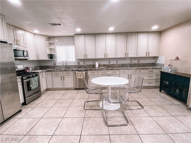 kitchen featuring tasteful backsplash, sink, light tile patterned floors, and stainless steel appliances