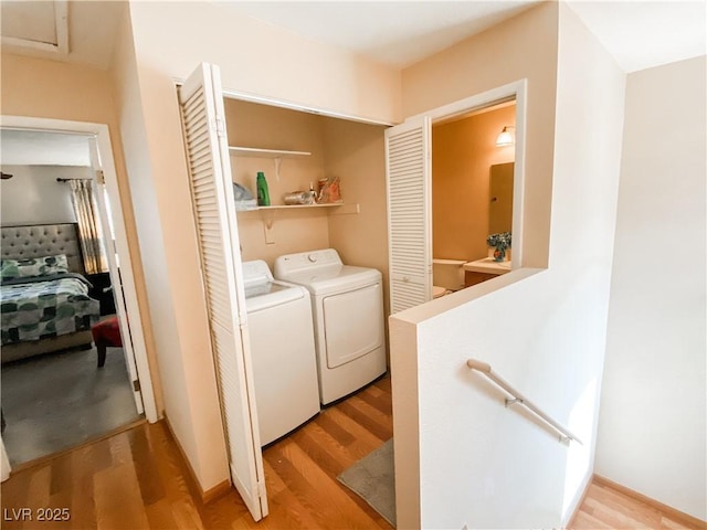 clothes washing area with washer and dryer and light hardwood / wood-style flooring