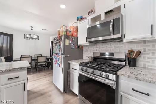 kitchen featuring white cabinetry, appliances with stainless steel finishes, pendant lighting, and decorative backsplash