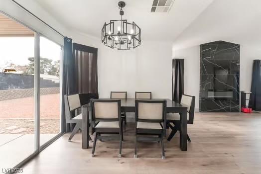 dining area featuring hardwood / wood-style flooring, lofted ceiling, and an inviting chandelier