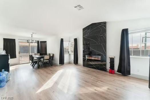 living room with a high end fireplace, a chandelier, and light wood-type flooring