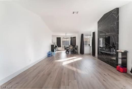 unfurnished living room featuring an inviting chandelier and wood-type flooring