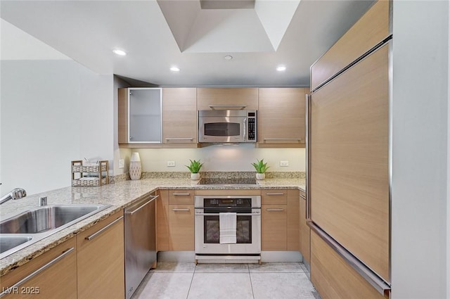 kitchen featuring sink, appliances with stainless steel finishes, light stone counters, light tile patterned flooring, and light brown cabinets