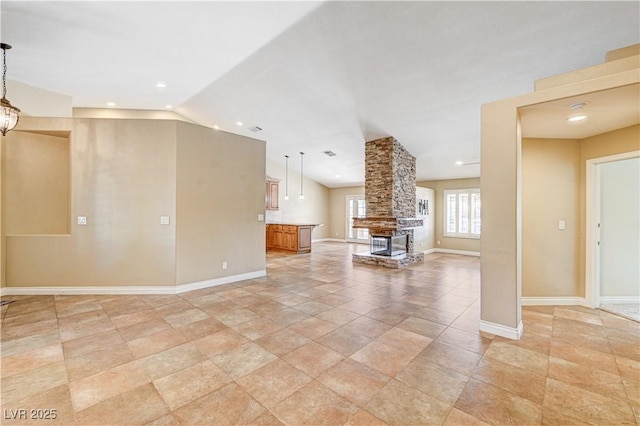 unfurnished living room with vaulted ceiling, a stone fireplace, and a notable chandelier