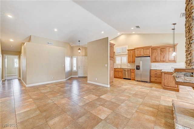 kitchen with high vaulted ceiling, tasteful backsplash, hanging light fixtures, light stone counters, and stainless steel appliances