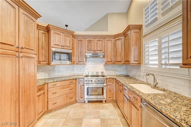 kitchen with vaulted ceiling, stainless steel appliances, light stone countertops, and sink