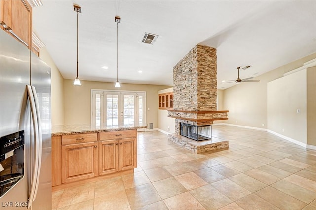 kitchen with light tile patterned flooring, decorative light fixtures, stainless steel fridge with ice dispenser, light stone countertops, and french doors