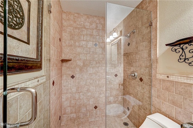 bathroom with toilet, tile walls, a textured ceiling, and walk in shower