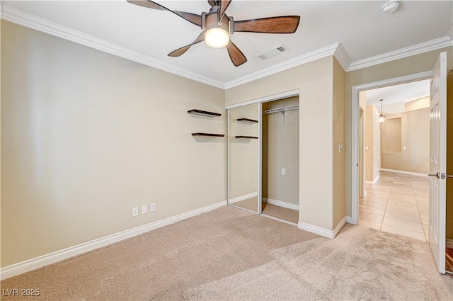 unfurnished bedroom with crown molding, light colored carpet, ceiling fan, and a closet