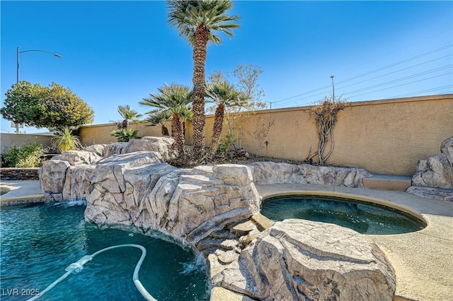 view of swimming pool featuring pool water feature and an in ground hot tub