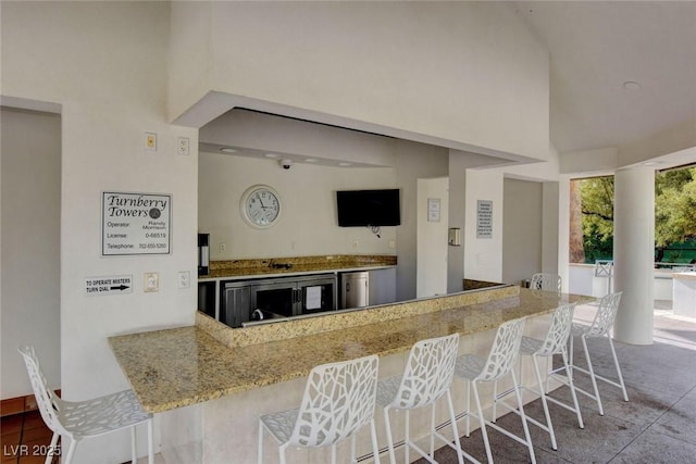 kitchen featuring dishwasher, a towering ceiling, a breakfast bar area, and kitchen peninsula