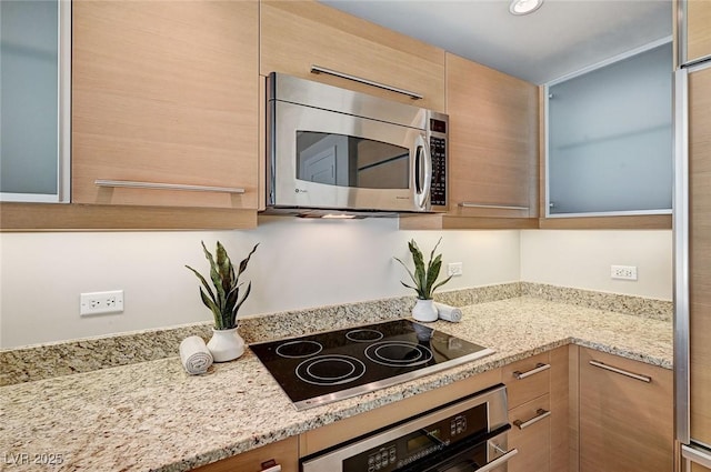 kitchen with light stone counters, light brown cabinets, and appliances with stainless steel finishes