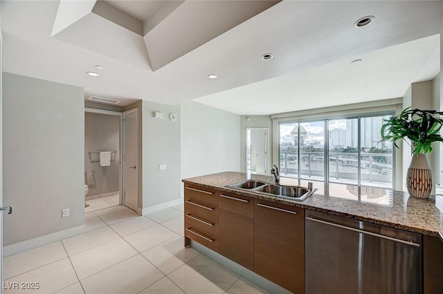 kitchen with light tile patterned flooring, dishwasher, sink, dark stone countertops, and dark brown cabinets