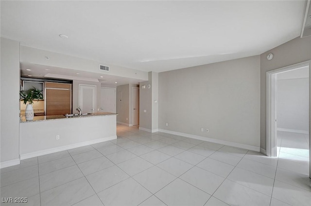 unfurnished living room with sink and light tile patterned floors