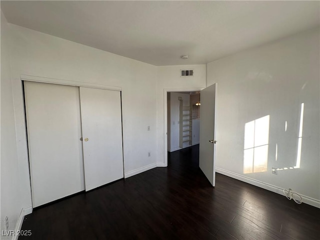 unfurnished bedroom featuring a closet and dark hardwood / wood-style floors