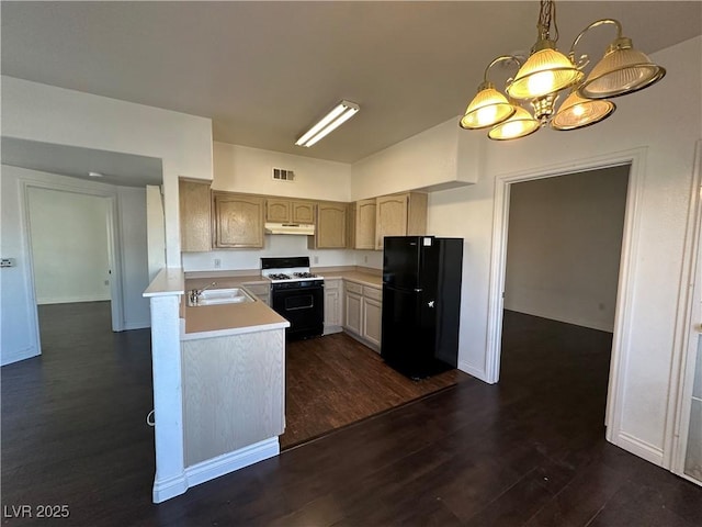 kitchen featuring hanging light fixtures, light brown cabinets, black refrigerator, dark hardwood / wood-style floors, and range with gas stovetop