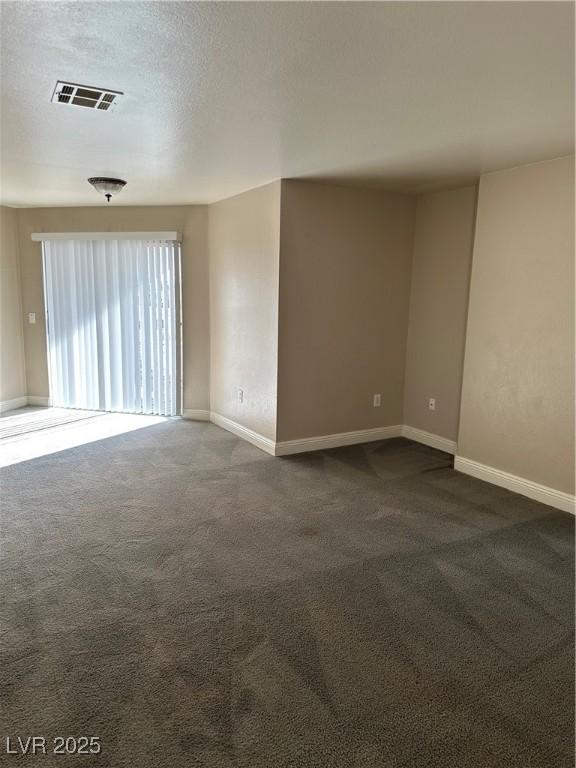 spare room featuring a textured ceiling and dark colored carpet