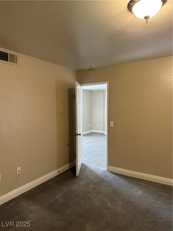 unfurnished room featuring dark colored carpet and a textured ceiling