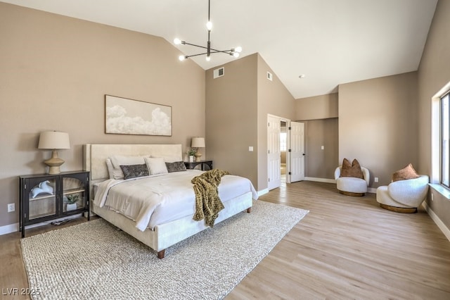 bedroom with a chandelier, high vaulted ceiling, and light hardwood / wood-style flooring