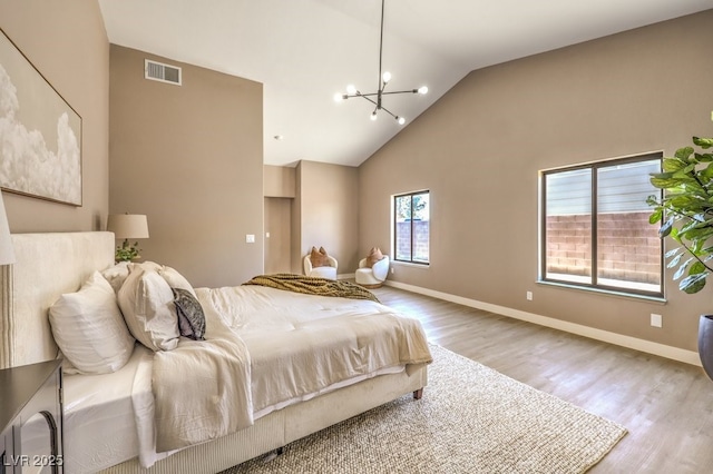 bedroom with wood-type flooring, high vaulted ceiling, and a notable chandelier