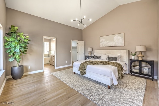 bedroom with high vaulted ceiling, connected bathroom, a notable chandelier, a walk in closet, and light wood-type flooring