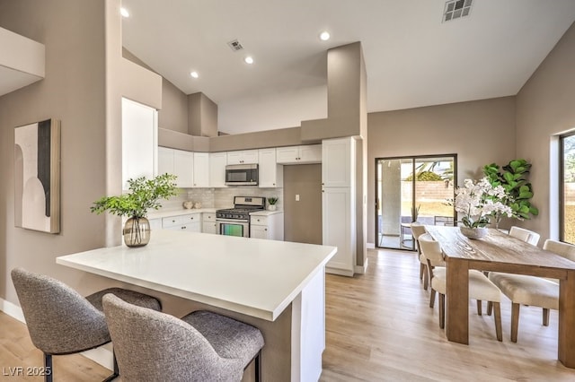 kitchen featuring tasteful backsplash, white cabinetry, a breakfast bar area, kitchen peninsula, and stainless steel appliances