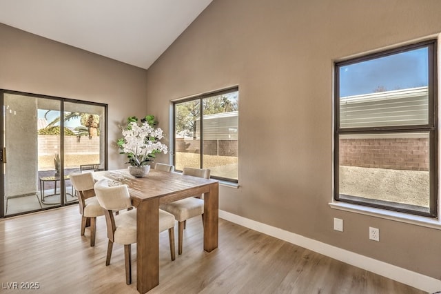 dining space featuring high vaulted ceiling and light wood-type flooring