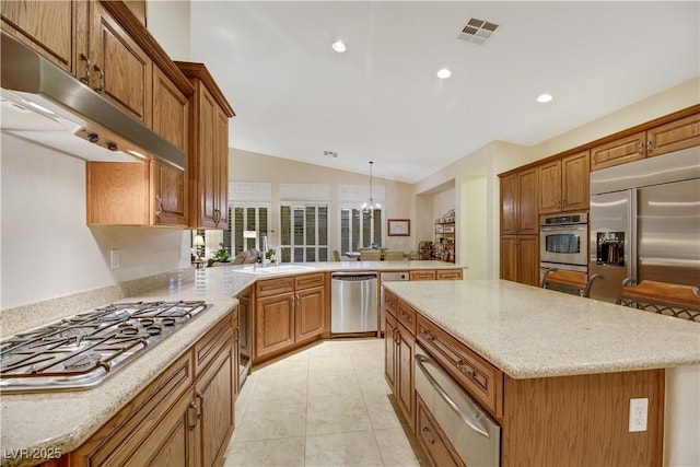 kitchen featuring stainless steel appliances, decorative light fixtures, a center island, and sink