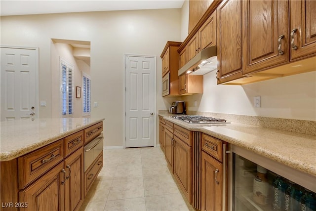 kitchen with light stone counters, light tile patterned floors, beverage cooler, and appliances with stainless steel finishes