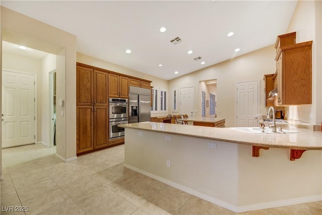 kitchen featuring lofted ceiling, sink, a breakfast bar, stainless steel appliances, and kitchen peninsula