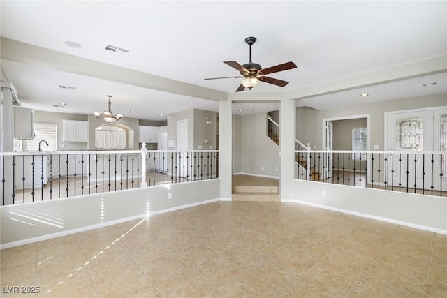 tiled empty room featuring sink and ceiling fan with notable chandelier