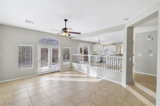 spare room with light tile patterned floors and ceiling fan with notable chandelier