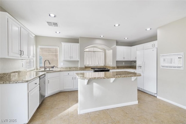 kitchen featuring sink, white cabinetry, a center island, stainless steel appliances, and light stone countertops