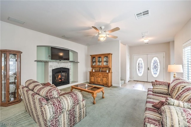 carpeted living room featuring a tile fireplace, french doors, and ceiling fan